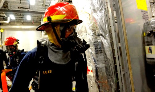 US Navy 100327-N-7653W-147 Chief Operation Specialist Anthony Morales help Sailors contain a fire during a damage control training drill