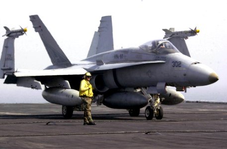 US Navy 030625-N-9319H-016 A plane director prepares to assist an F-A-18 Hornet to one of four steam driven catapults during flight operations on the flight deck aboard USS Nimitz (CVN 68)