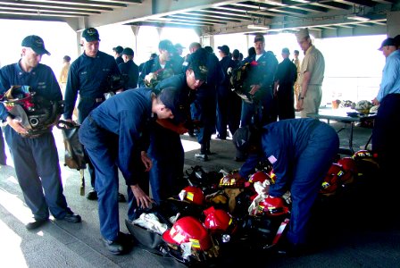 US Navy 030708-N-0000X-002 Crewmembers aboard the submarine tender USS Emory S. Land (AS 39) check out fire fighting gear to hose team members fighting a brush fire on the island of Santo Stefano