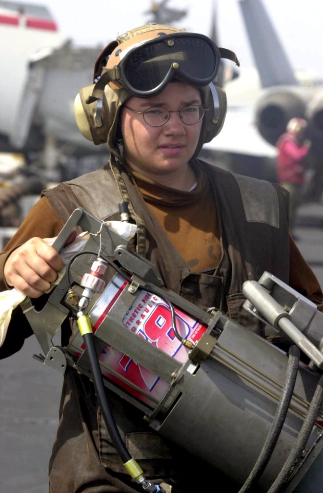 US Navy 030625-N-2385R-003 Aircrew Survival Equipmentman Airman Kate Newbold carries a Hydraulic Servicing Unit (HSU) to a F-A-18 Hornet on the flight deck aboard USS Nimitz (CVN 68)