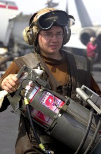 US Navy 030625-N-2385R-003 Aircrew Survival Equipmentman Airman Kate Newbold carries a Hydraulic Servicing Unit (HSU) to a F-A-18 Hornet on the flight deck aboard USS Nimitz (CVN 68)