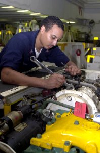 US Navy 030626-N-2385R-002 Aviation Support Equipment Technician 2nd Class Keyon Jenkins from Los Angeles, Calif., performs maintenance on an aircraft towing tractor in the hangar bay aboard USS Nimitz (CVN 68)