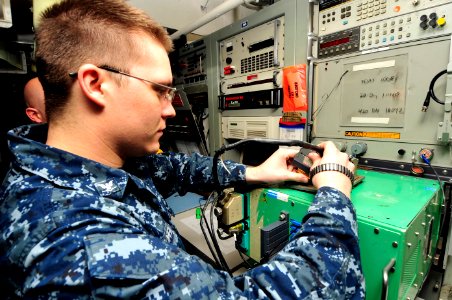 US Navy 100505-N-6935K-004 Aviation Electrician's Mate 3rd Class Shane Rogers checks a power supply unit for aircraft