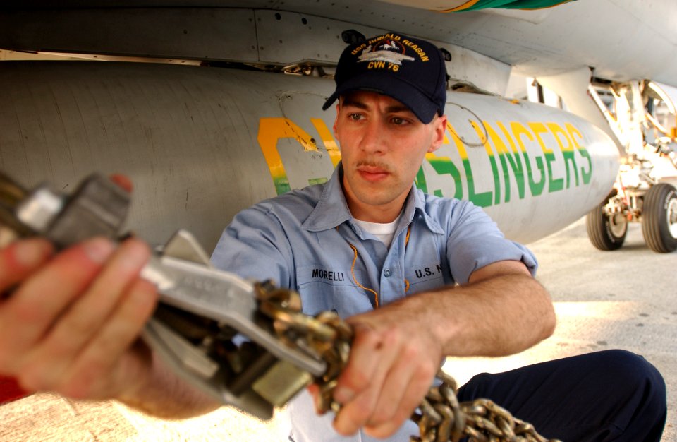 US Navy 030709-N-0696M-011 Airman Will Morelli, chains an F-A-18 Hornet from the Gunslingers of Strike Fighter Squadron One Zero Five (VFA-105) to an aircraft elevator