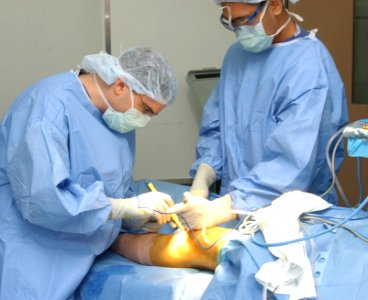 US Navy 030710-N-0000W-001 Orthopedics Department Head Lt. Cmdr. Daniel J. Solomon performs exploratory surgery during an anterior crucuate ligament reconstruction procedure, as Hospital Corpsman 3rd Class Andrew S. Caldejon as