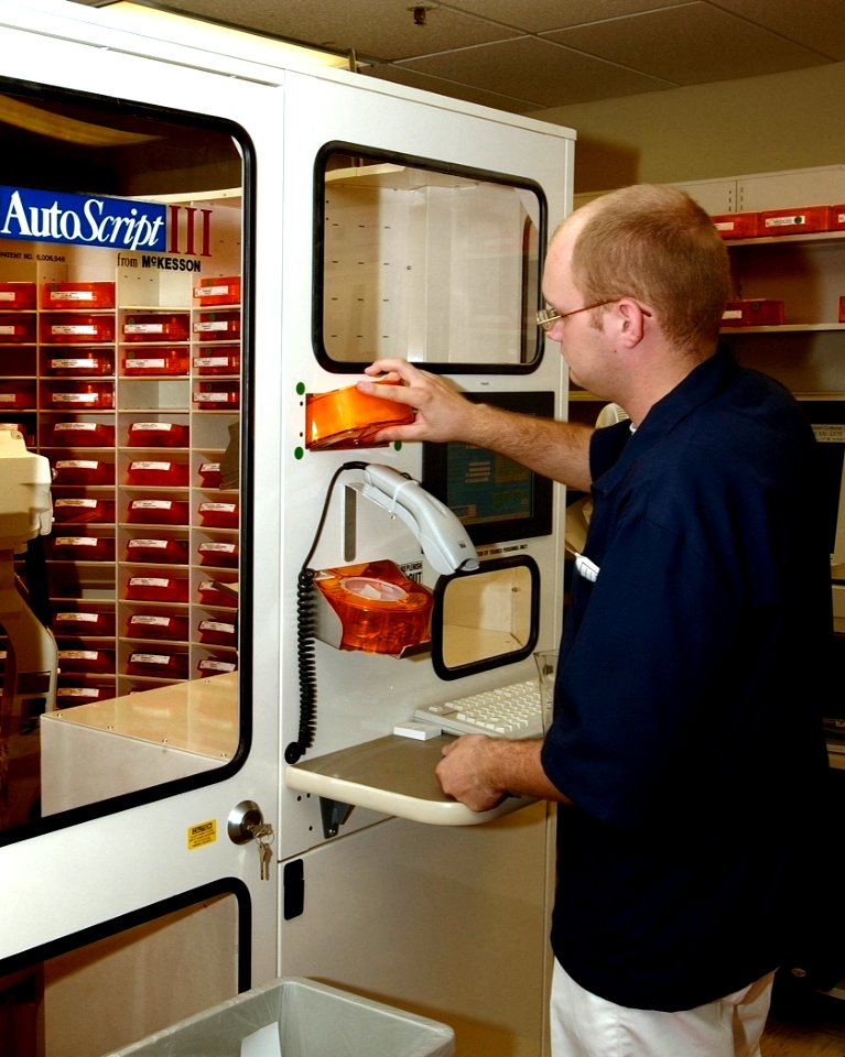 US Navy 030819-N-9593R-096 Hospitalman Randy Connelly, of Breezewood, Penna., feeds a medication bin to the Autoscript III robot at the National Naval Medical Center in Bethesda, Maryland