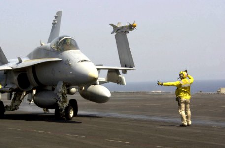 US Navy 030701-N-9319H-011 Chief Aviation Boatswain's Mate Michael Lauricella directs an F-A-18 Hornet into position for launch from one of the four steam powered catapults on the flight deck aboard USS Nimitz (CVN 68)