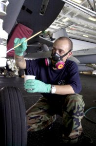 US Navy 030716-N-0413R-008 Aviation Structural Mechanic 3rd Class Ivan Irizarry of Harlem, N.Y., applies a coat of paint to the nose landing gear of an aircraft, in the Hanger Bay aboard USS Nimitz (CVN 68)