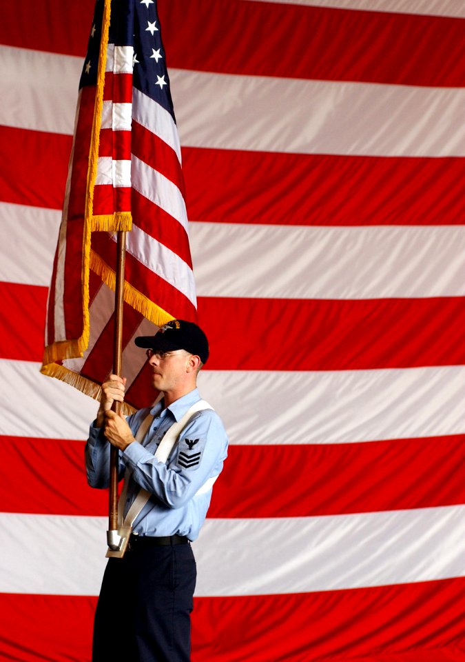 US Navy 030709-N-0696M-008 Personnelman 1st Class William E. Evans carries the National Ensign during color guard rehearsals in preparation for the ship's commissioning ceremony, scheduled for July 12th, 2003