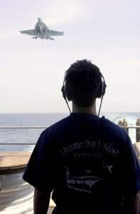 US Navy 030726-N-2143T-002 Seaman Thomas Wisnieski of Philadelphia, Pa., stands the aft look out watch on the fantail while an F-18 Super Hornet makes an arrested landing aboard USS Nimitz (CVN 68)