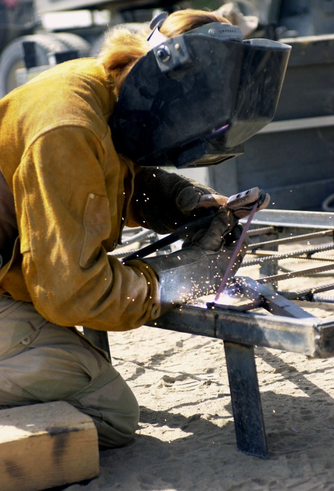 US Navy 030701-N-9455K-091 Steelworker 2nd Class Paula Miller assigned to Naval Mobile Construction Battalion Seven (NMCB-7) Charlie Company, displays some of her handy work while welding bars on a door that will be used in a j
