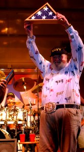 US Navy 030911-C-0368R-003 Country musician Charlie Daniels dons a Navy ballcap and waves the National Ensign presented to him by Command Master Chief Michael Tsikours of Recruit Training Command
