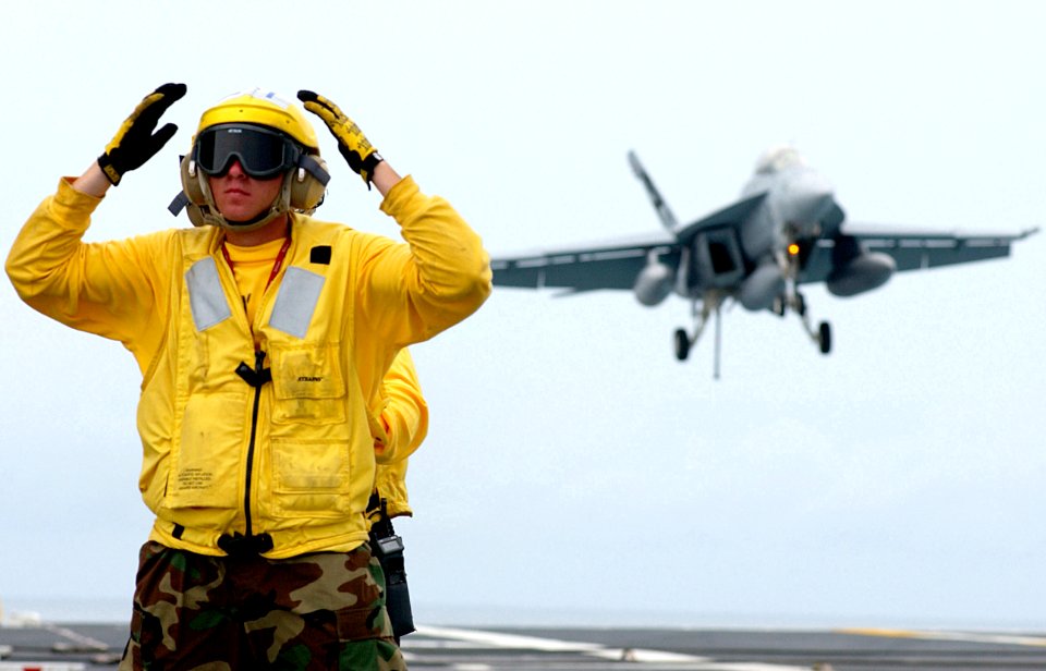 US Navy 030725-N-0696M-022 Airman Dylan Wondra directs aircraft on the flight deck, while an F-A-18F Super Hornet makes an arrested landing on the flight deck aboard USS Ronald Reagan (CVN 76)