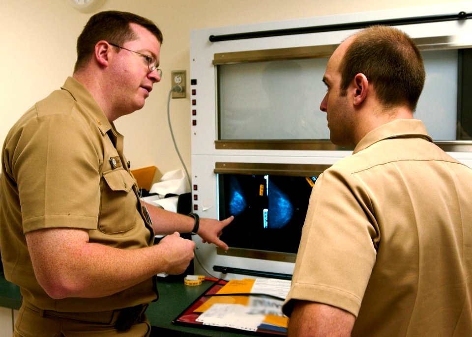 US Navy 030820-N-9593R-004 U.S. Navy doctors Lt. Cmdr Ralph Pickard, left, and Ens. Jesse Rohloff study a patient's mammography film at the National Naval Medical Center in Bethesda, Md