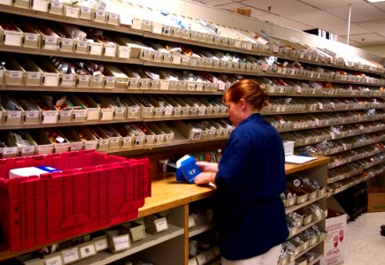 US Navy 030819-N-9593R-078 A Navy hospital corpsman unwraps medication to replenish one of the hundreds of bins in the pharmacy at the National Naval Medical Center in Bethesda, Maryland