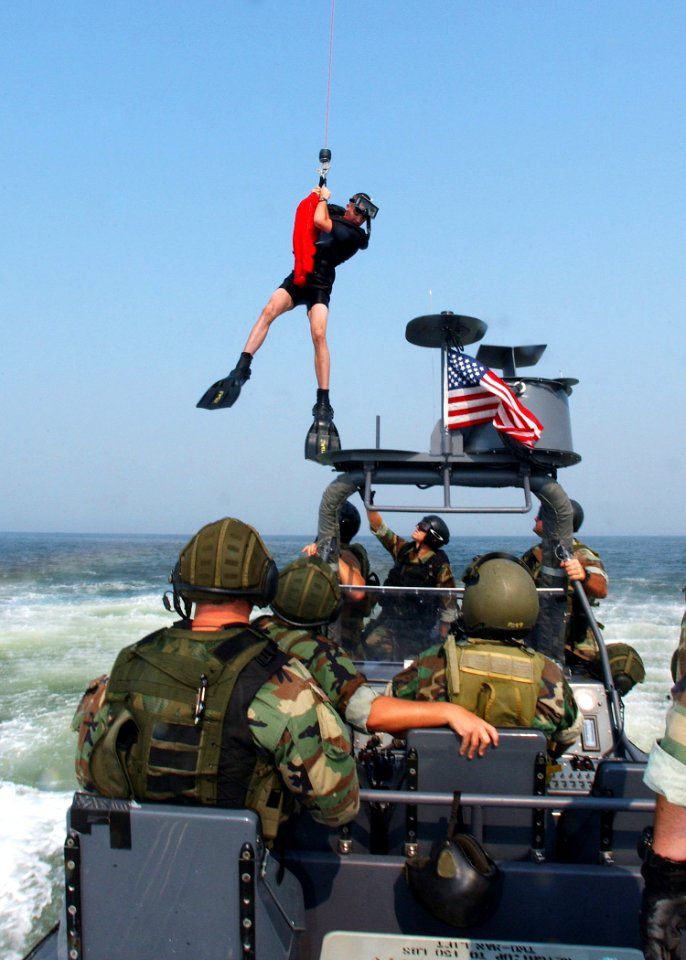 US Navy 030826-N-4374S-015 A rescue swimmer assigned to the Chargers of Helicopter Combat Support Squadron SIX (HC-6) hovers over a Rigid Hull Inflatable Boat (RHIB) during recovery operations