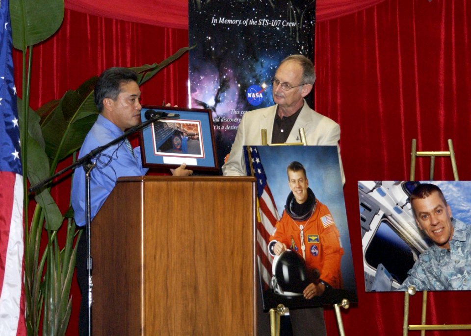 US Navy 030829-N-7293M-019 The Honorable Felix P. Camacho, Governor of Guam, presents a photo of U.S. Navy Cmdr. and astronaut William C. McCool with the Guam flag to Mr. William A. Hall, principal of Depart of Defense Educatio