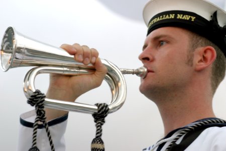 US Navy 030901-N-3228G-001 A sideboy aboard the Royal Australian Navy frigate HMAS Warramunga (FFH 152), sounds his bugle to render honors to a U.S. Navy flag officer