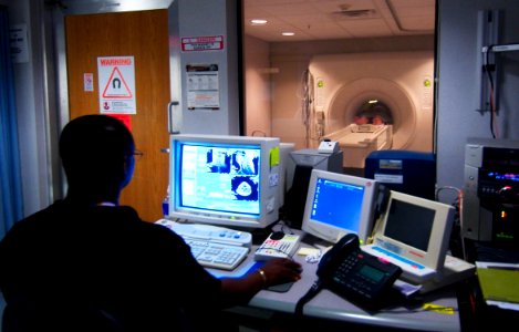 US Navy 030819-N-9593R-228 Civilian technician, Jose Araujo watches as a patient goes through a Magnetic Resonance Imaging, (MRI) machine