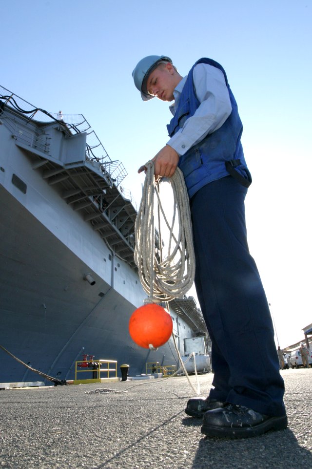 US Navy 030829-N-3228G-003 Gas Turbine Systems Technician Fireman Alan Marlin gathers up the heaving line after mooring the amphibious assault ship USS Peleliu (LHA 5)
