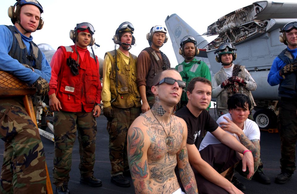US Navy 030827-N-8273J-003 The rock bank Blink-182 poses for a photo with crewmembers during a United Services Organization (USO) visit aboard USS Nimitz (CVN 68)