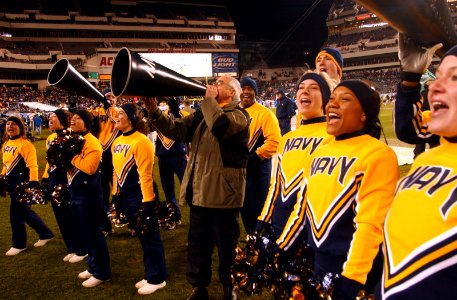 US Navy 031206-N-2568S-001 Secretary of the Navy, Gordon R. England joins the Naval Academy Cheerleaders in leading the Midshipmen in a cheer