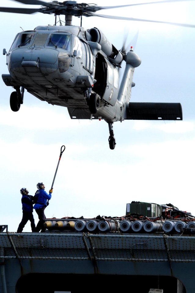 US Navy 100909-N-7605J-060 An MH-60S Sea Hawk helicopter hovers as Sailors connect a cargo pendant
