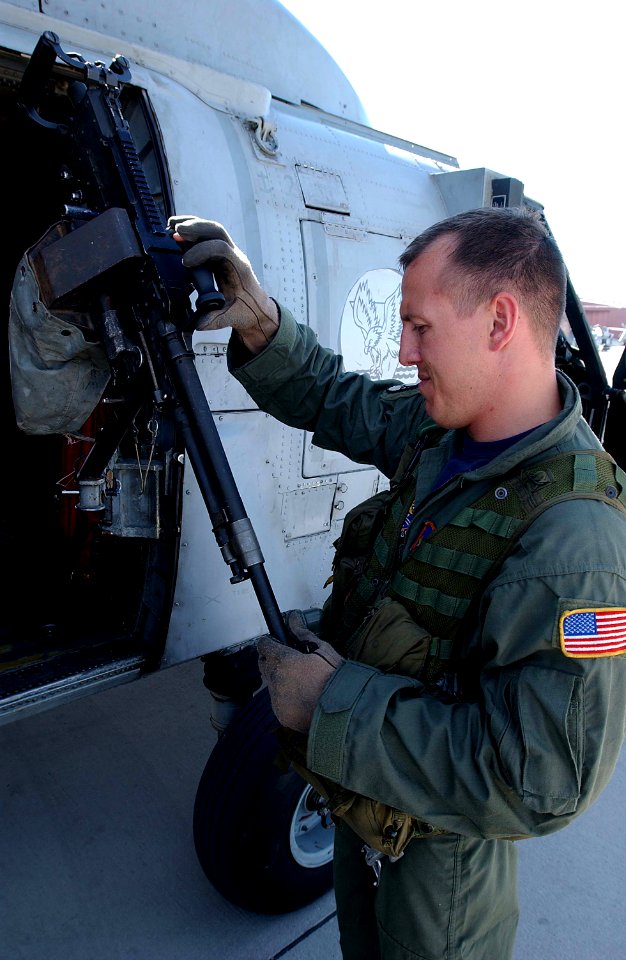 US Navy 030805-F-4884R-002 Aviation Warfare Systems Operator 1st Class Ivan Diaz inspects the door gun in preparation for a mission during Desert Rescue XI