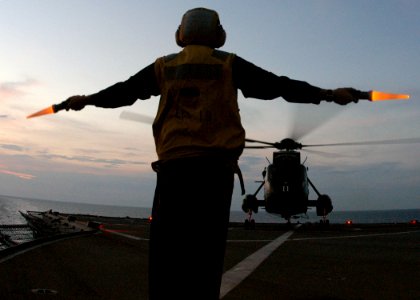 US Navy 030831-N-8955H-008 Boatswain's Mate 1st Class Joseph Mullen, from Seattle, Wash., provides the hover signal to the pilot of a helicopter