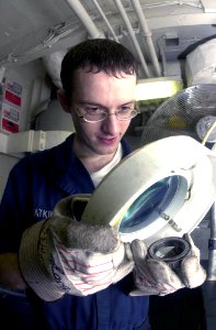 US Navy 030903-N-2143T-001 Aviation Structural Mechanic Airman John Watkins uses a magnifying glass to check for defects