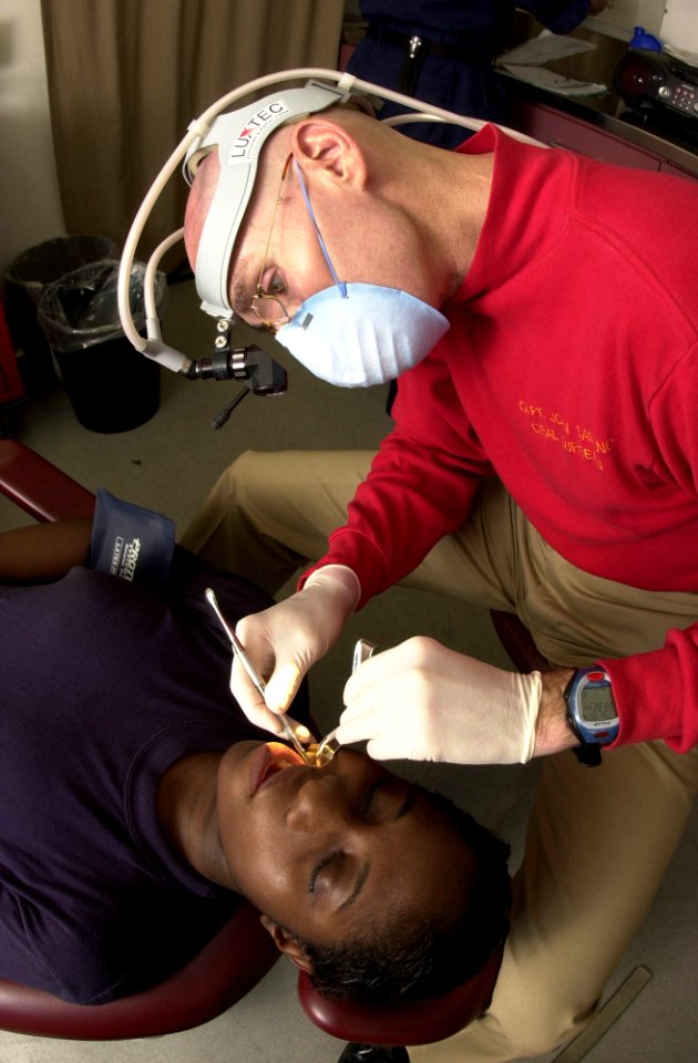 US Navy 031002-N-1577S-004 Oral Surgeon Captain John Le Banc, from Hillsburrow, Ill., removes a wisdom tooth from Airman Latoya Vassel, from Jersey City, N.J., aboard USS Nimitz (CVN 68)