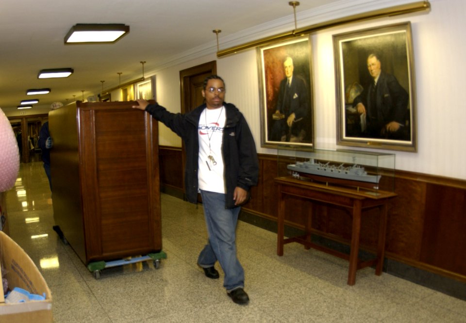 US Navy 031113-N-9693M-008 Office Mover employees roll the Under Secretary of the Navy's desk through the Dept. of the Navy's Executive Corridor
