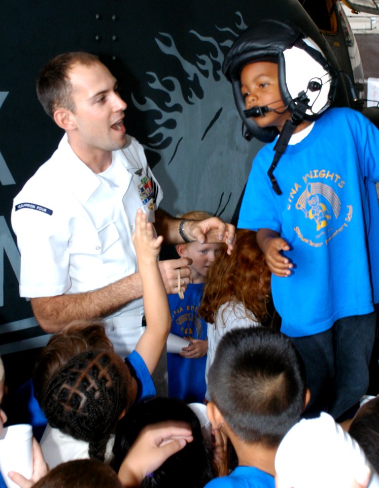 US Navy 031003-N-5821W-003 Aircrew Survival Equipmentman 1st Class Ryan Fitzgerald lets a first-grade student from Naval Air Station (NAS) Sigonella's Stephen Decatur Elementary School try on a helmet