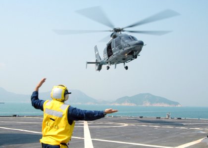 US Navy 031101-N-8955H-002 Landing Signalman Enlisted (LSE) Boatswain's Mate 1st Class Joseph Mullen, from Seattle, Wash., signals an EC-155 Dauphin helicopter from the Hong Kong Government Flying Service to depart the flight deck