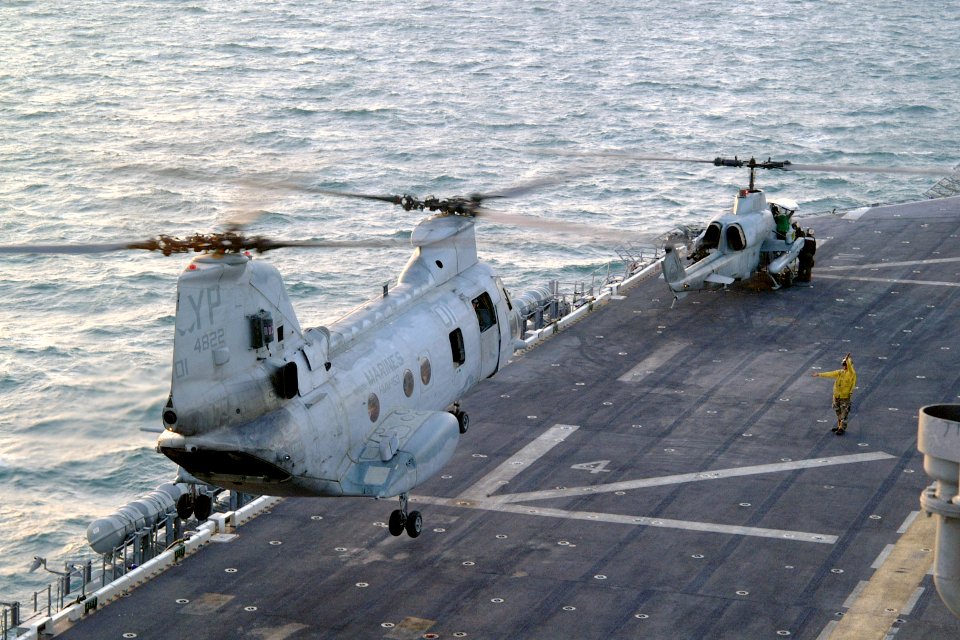 US Navy 031006-N-6895M-010 CH-46 Sea Knight and an AH-1W Cobra lift off from the flight deck of USS Peleliu (LHA-5)