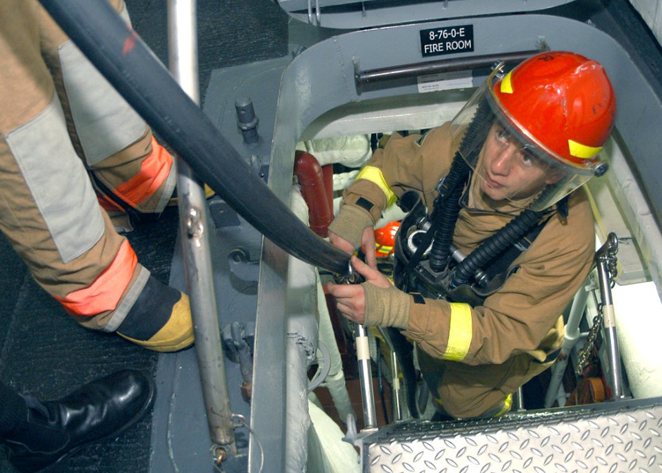 US Navy 031013-N-8955H-004 Mess Management 3rd Class Vladimir Lisser, from Denver, Colo., helps return an Aqueous Film Forming Foam (AFFF) hose