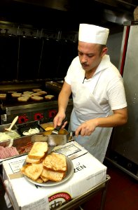 US Navy 031107-N-5821P-004 Mess Management Specialist Seaman Apprentice Hernan Bravo, from Miami, Fla., works the grill in the chief's mess self-serve line aboard USS Kitty Hawk (CV 63)