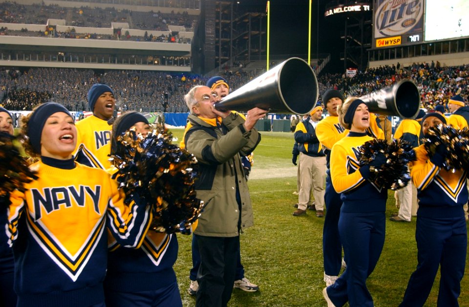 US Navy 031206-N-2568S-002 Secretary of the Navy, Gordon R. England joins the Naval Academy Cheerleaders in leading the Midshipmen in a cheer