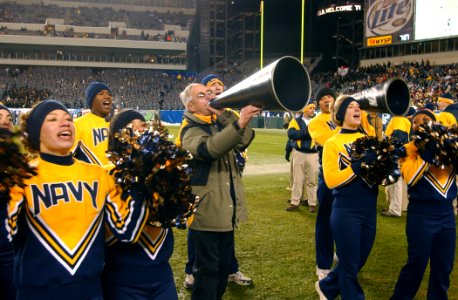 US Navy 031206-N-2568S-002 Secretary of the Navy, Gordon R. England joins the Naval Academy Cheerleaders in leading the Midshipmen in a cheer