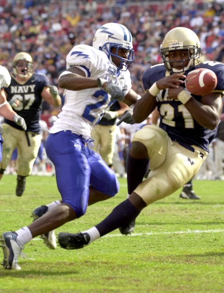 US Navy 031004-N-9693M-521 Navy slotback Tony Lane bobbles the ball and is hit by Air Force halfback Jason Boman following a caught 10-yard touchdown pass