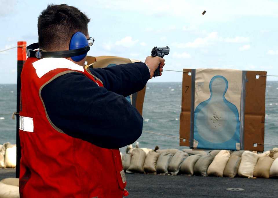 US Navy 031022-N-6653C-001 A sailor shoots a 9mm pistol for small arms qualification on elevator three as part of the ship's force protection aboard USS George Washington (CVN 73)