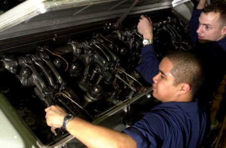 US Navy 030910-N-6536T-003 Fireman Ronnie Panganiban, from San Diego, Calif., tightens the fuel rack in a diesel engine as Engineman 2nd Class Tim Chidester, from Ogden, Utah, supervises in the forward diesel generator room