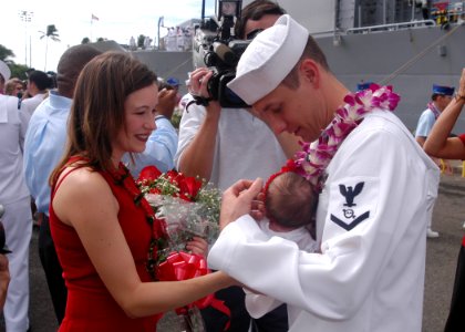 US Navy 031102-N-1618Z-103 Greeted by his wife and daughter, Operation's Specialist 3rd Class Jeromy Turner holds his ten-day-old daughter for the first time upon his arrival home from deployment aboard the USS Chosin (CG 65) photo