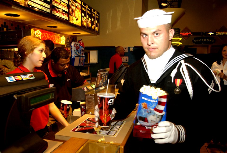 US Navy 031106-N-9693M-001 Seaman Apprentice Chris Firking carries popcorn and soda into a theater