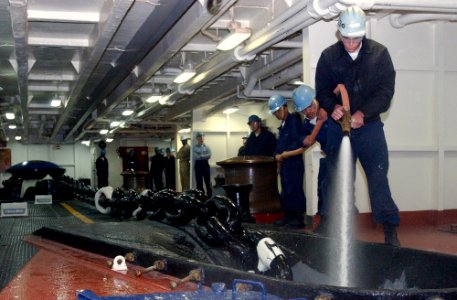 US Navy 031021-N-5821P-005 Boatswain's Mate 3rd Class Gilbert Gumba, from Suisan, Calif., uses a vari-nozzle to clean the anchor chain as it is brought back aboard after USS Kitty Hawk's (CV 63) first anchoring since