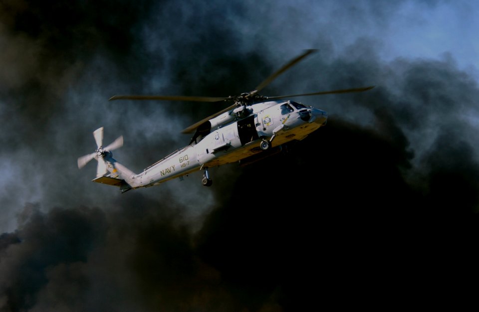US Navy 031108-N-5862D-127 Black smoke clouds rise from a pyrotechnic display as an HH-60H Seahawk helicopter demonstrates Combat Search and Rescue (CSAR) for the audience attending the Blue Angels homecoming air show at NAS Pe