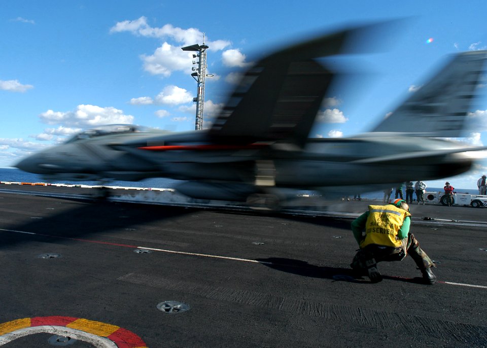 US Navy 031121-N-3986D-002 Aviation Boatswain's Mate 3rd Class Harrison Brookes from Virginia Beach, Va., braces himself as an F-14B Tomcat, assigned to Carrier Air Wing Seven (CVW-7) is launched