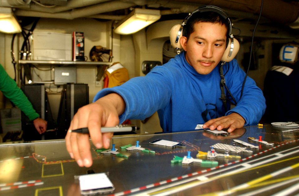 US Navy 031102-N-5821P-002 Working in flight deck control aboard USS Kitty Hawk (CV 63), Airman Darwin Cabadeana, from New York City, plots the locations of aircraft on the flight deck as he receives movement information throug