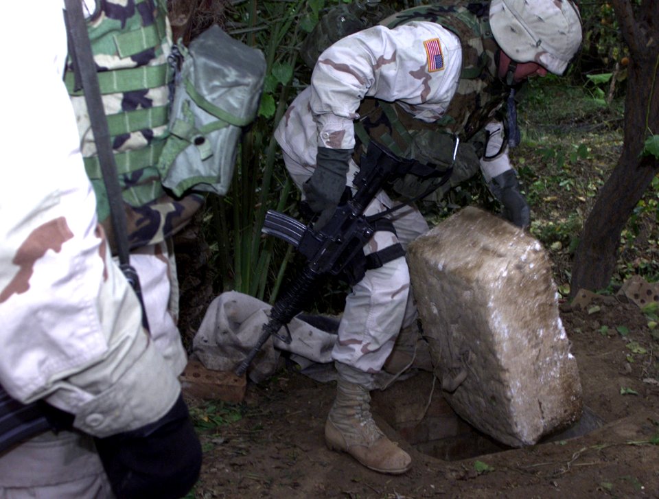 US Navy 031217-A-0000X-001 A member of the 1st Brigade Combat Team lifts a Styrofoam lid covering the hole where former Iraqi dictator Saddam Hussein was discovered hiding at the time of his capture