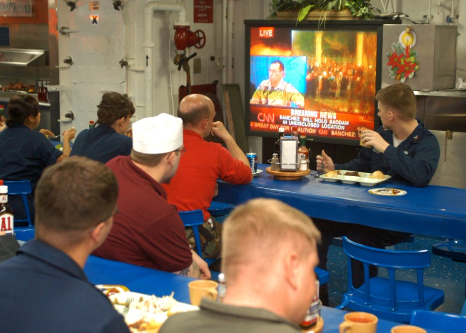 US Navy 031214-N-0715P-021 Sailors aboard the USS Peleliu (LHA 5) watch in interest during a live broadcast announcing the capture of former Iraqi Dictator, Saddam Hussein, on the ship's mess decks